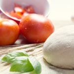 Bola de masa de pizza con dos tomates y albahaca